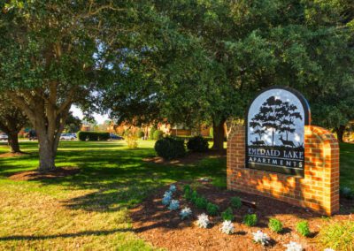 The entrance to the Woodlands at the Lake community, featuring a welcoming sign and lush greenery surrounding the pathway.